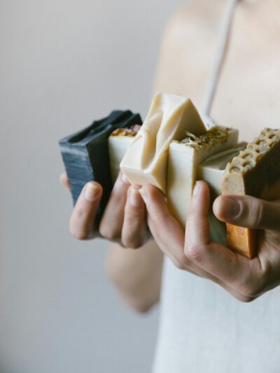 Close-up of hands holding diverse organic soaps in a delicate skin care setting.
